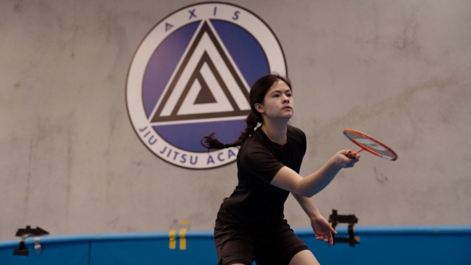 A junior player returns a shuttlecock at badminton